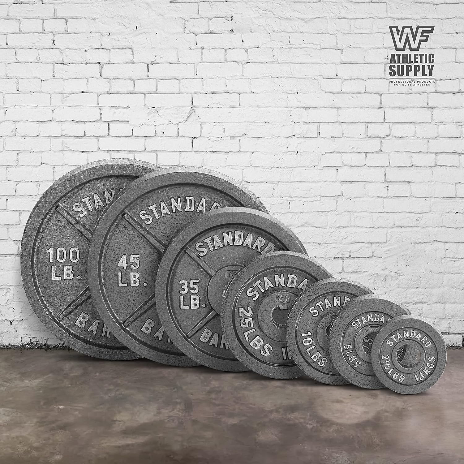 Set of weight plates against a white brick wall.