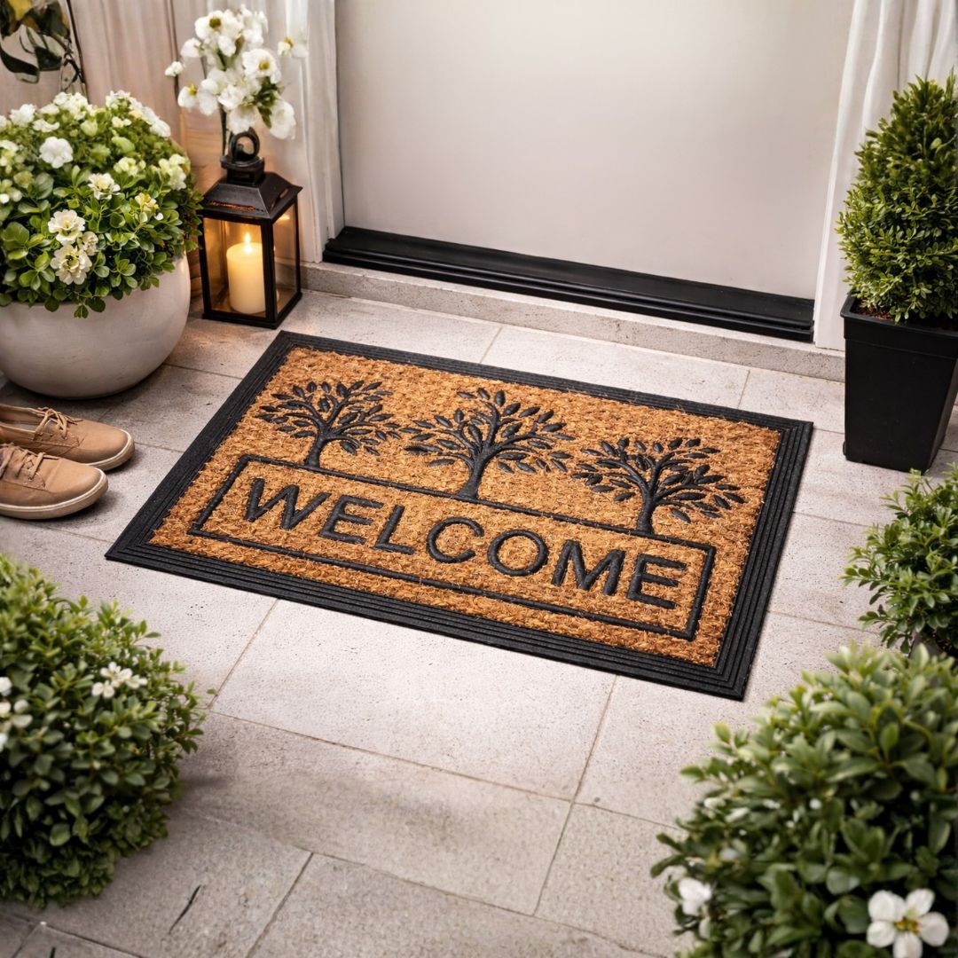 Tapete capacho de fibra de coco com estampa de árvores e texto Welcome posicionado em uma entrada decorada com vasos de plantas e lanterna