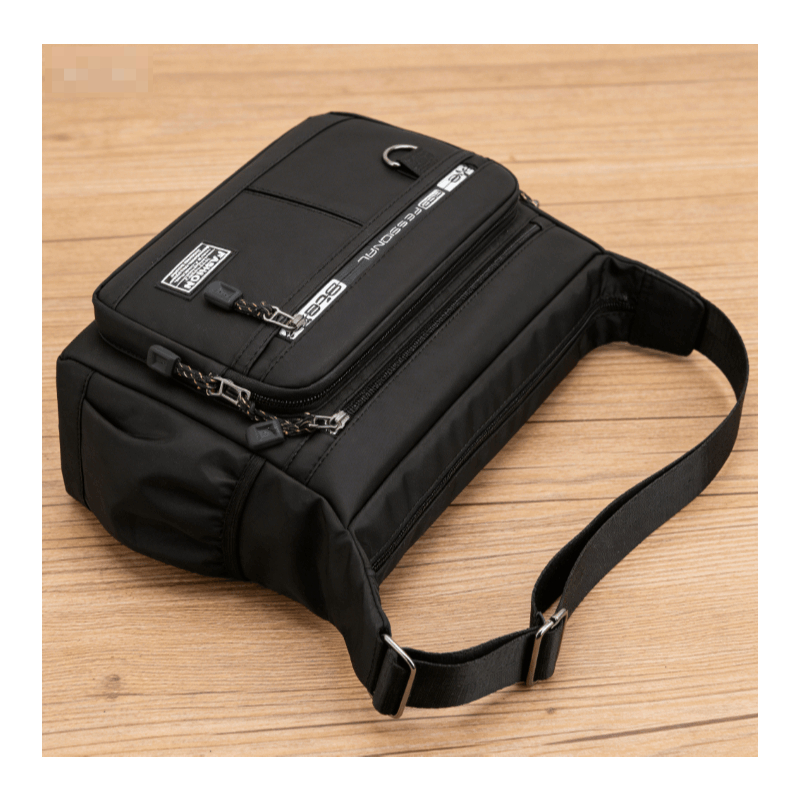 Bolsa tiracolo masculina na cor preta com detalhes em zíper e etiquetas decorativas