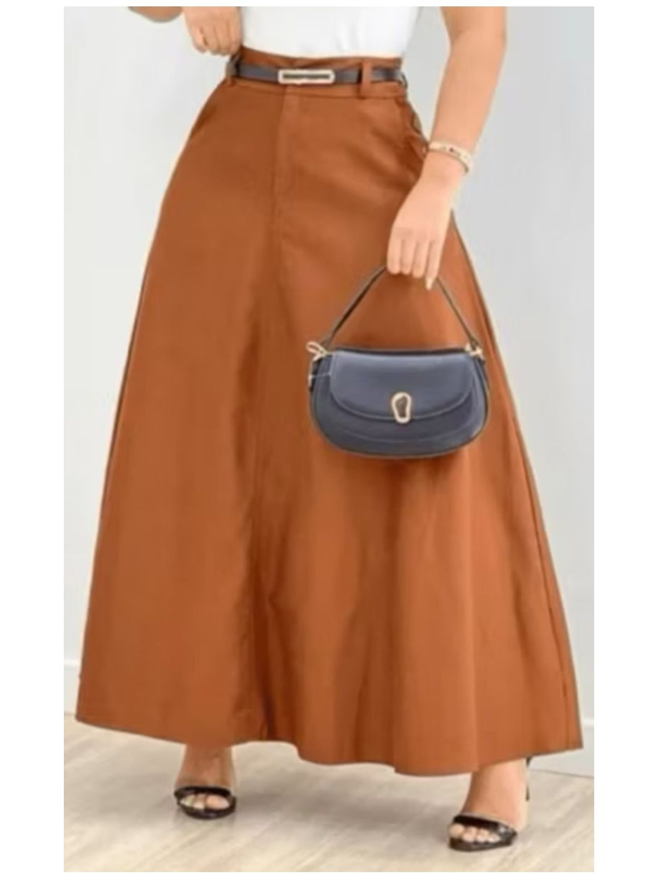 Detalhe em close da cintura de uma saia longa cor terracota com cinto preto e bolsa de mão