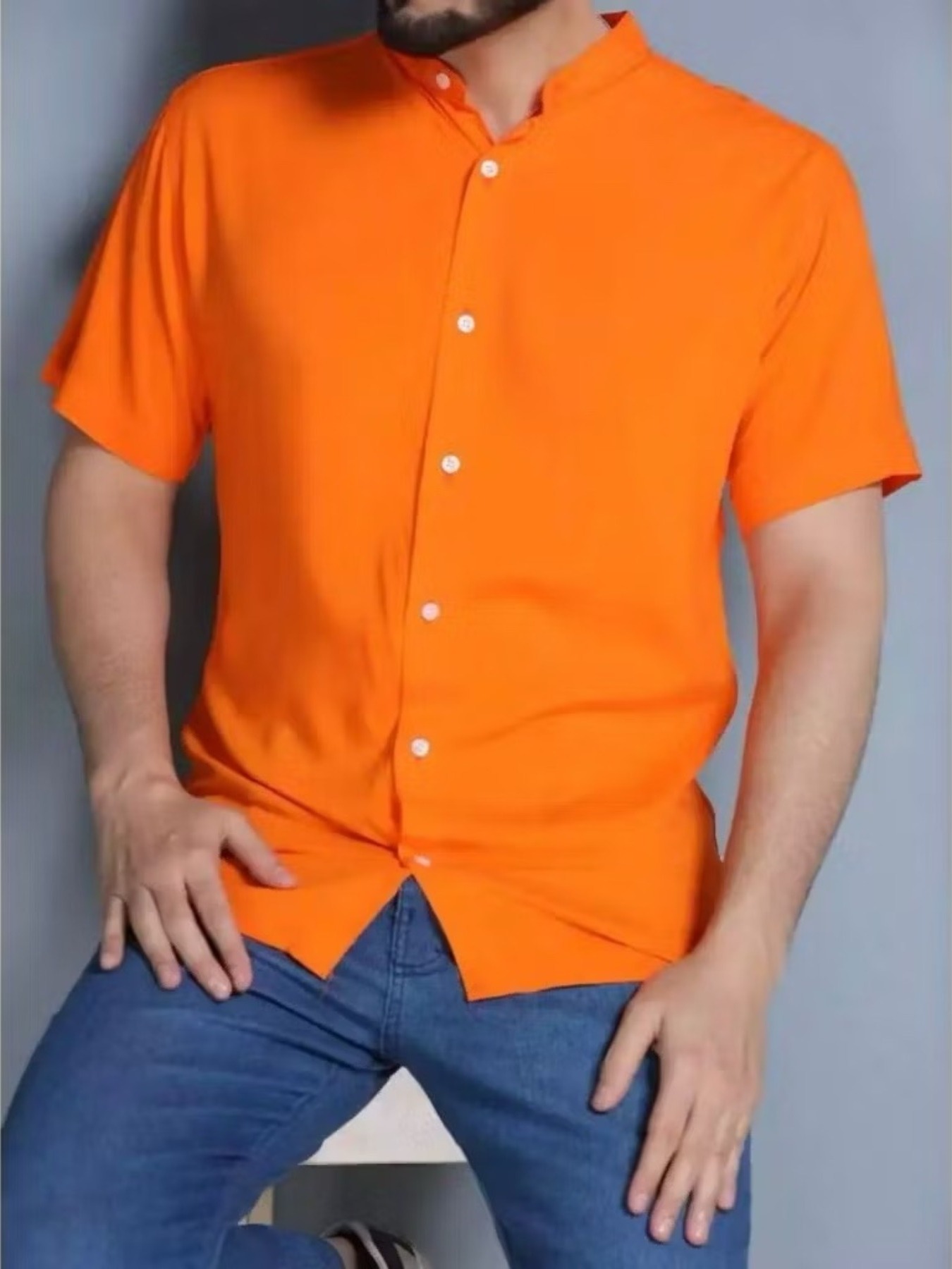 Homem vestindo camisa gola padre manga curta na cor laranja com calça jeans azul