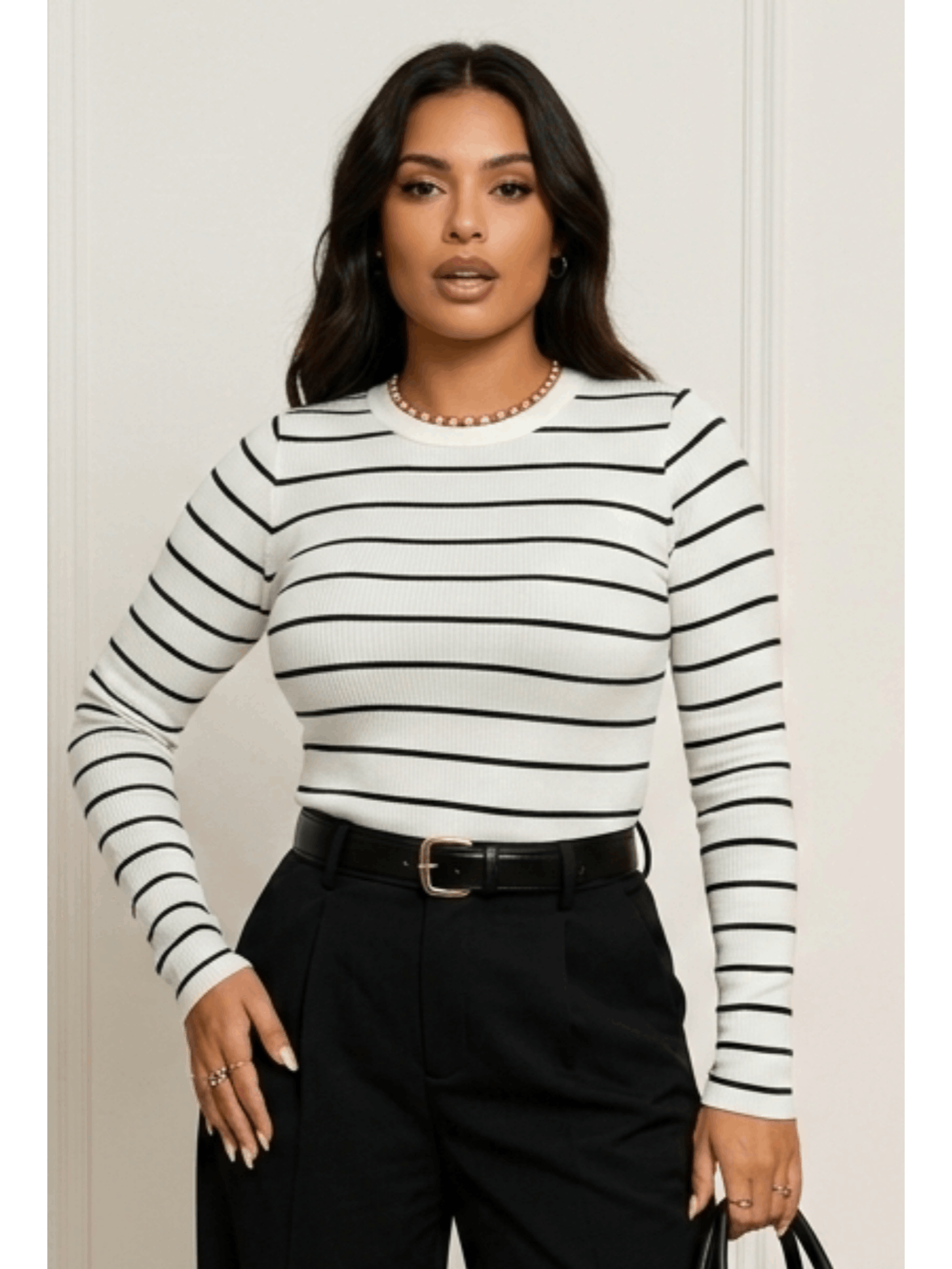Modelo usando blusa feminina branca com listras pretas, manga longa e gola canoa, combinada com cinto e calca preta