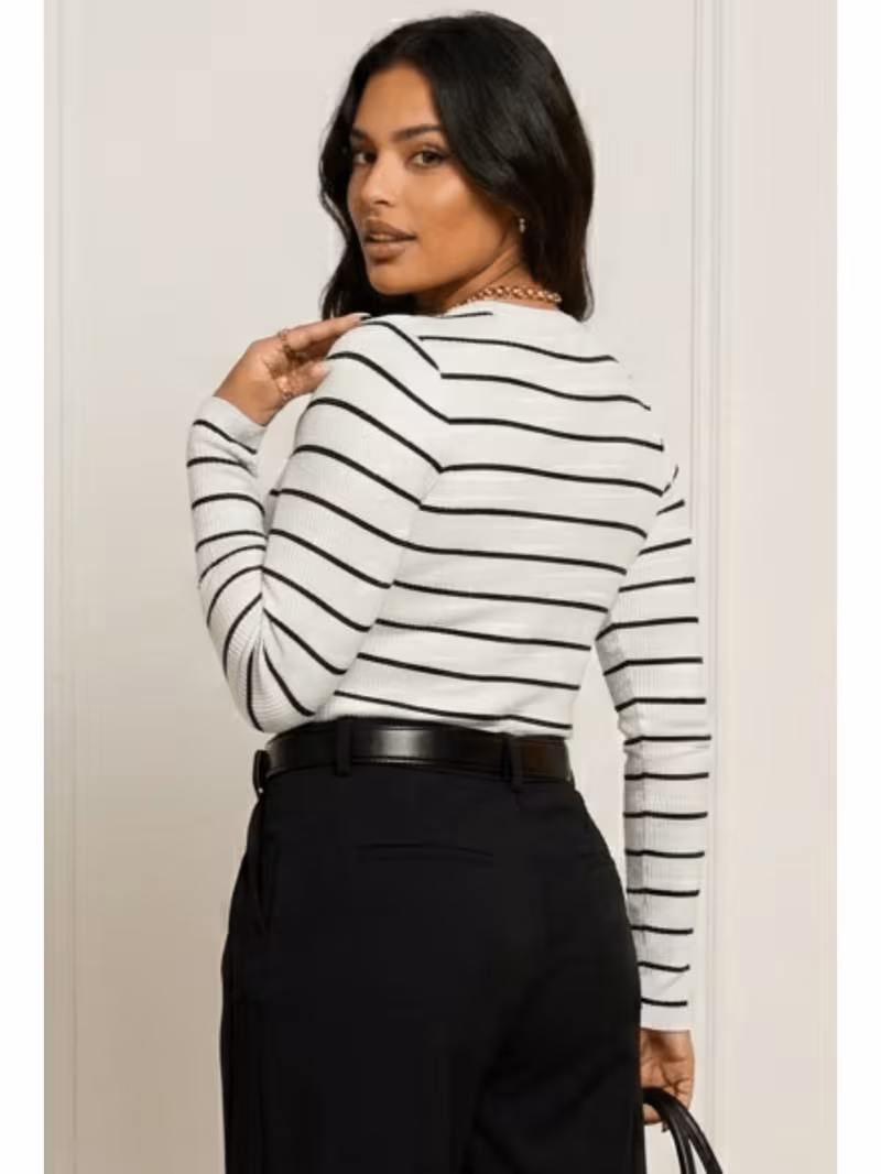 Vista posterior da modelo vestindo blusa feminina branca com listras pretas em tecido ribana