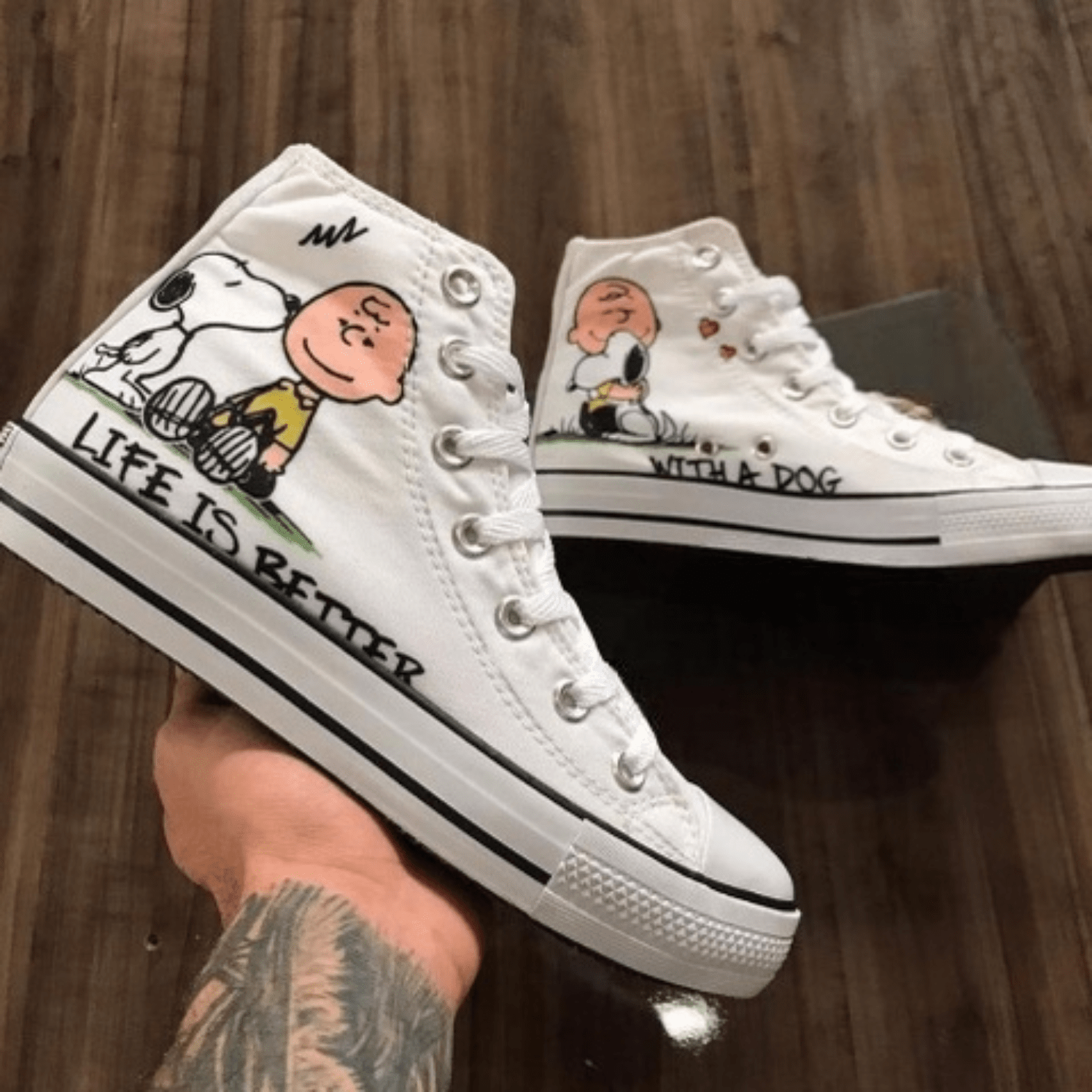 Tênis branco de cano alto com estampa de Charlie Brown e Snoopy, escrito "LIFE IS BETTER WITH A DOG".
