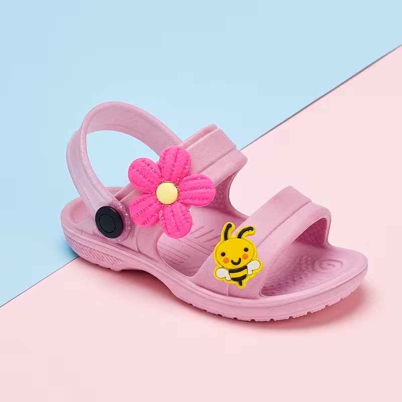 Sandalia infantil rosa com aplique de flor rosa e abelhinha sobre um fundo dividido em azul e rosa