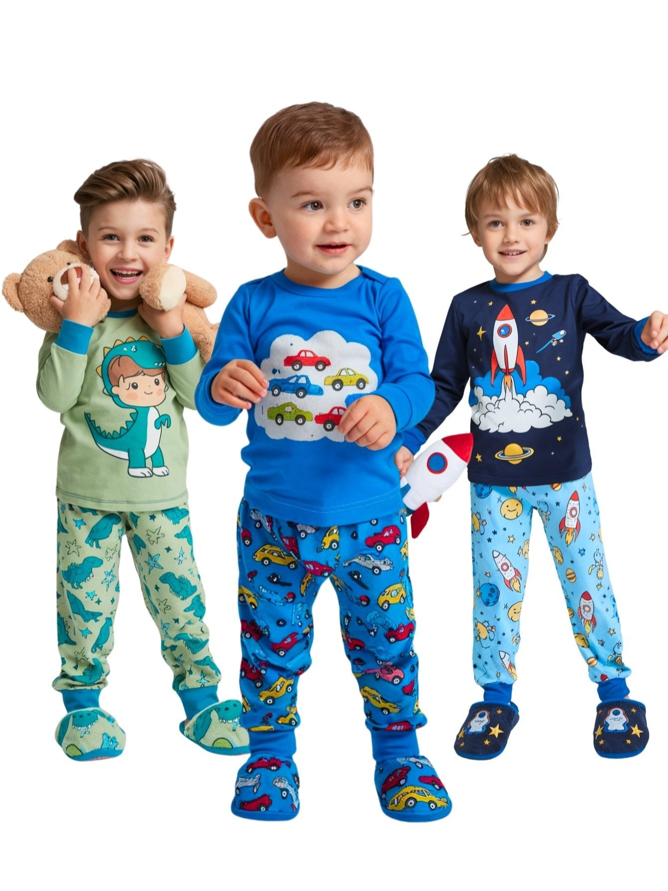 Três meninos posando com diferentes modelos de pijamas estampados: dinossauro verde, carros azuis e foguete espacial azul marinho.