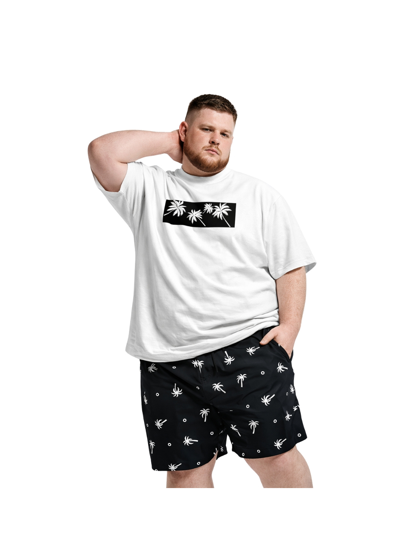 Homem plus size vestindo camiseta branca com estampa de palmeiras e short preto de tactel, vista frontal