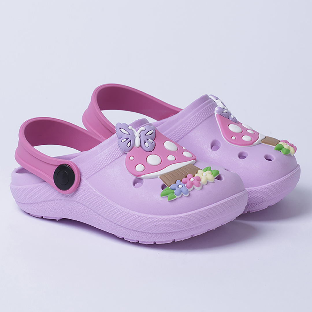 Par de sandálias babuche infantis na cor lilás com alça traseira rosa, decoradas com apliques de borboleta e cogumelo na parte superior