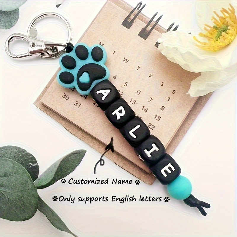 E-shop [Personalisiert] Ein personalisierbarer Silikon-Schlüsselanhänger mit Namensperlen, Hunde-Pfotenmuster und englischen Buchstaben -