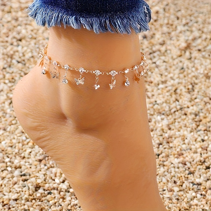 

Un bracelet de cheville à chaîne fine avec pendentif à pompon, incrusté de strass et de décoration géométrique pour .