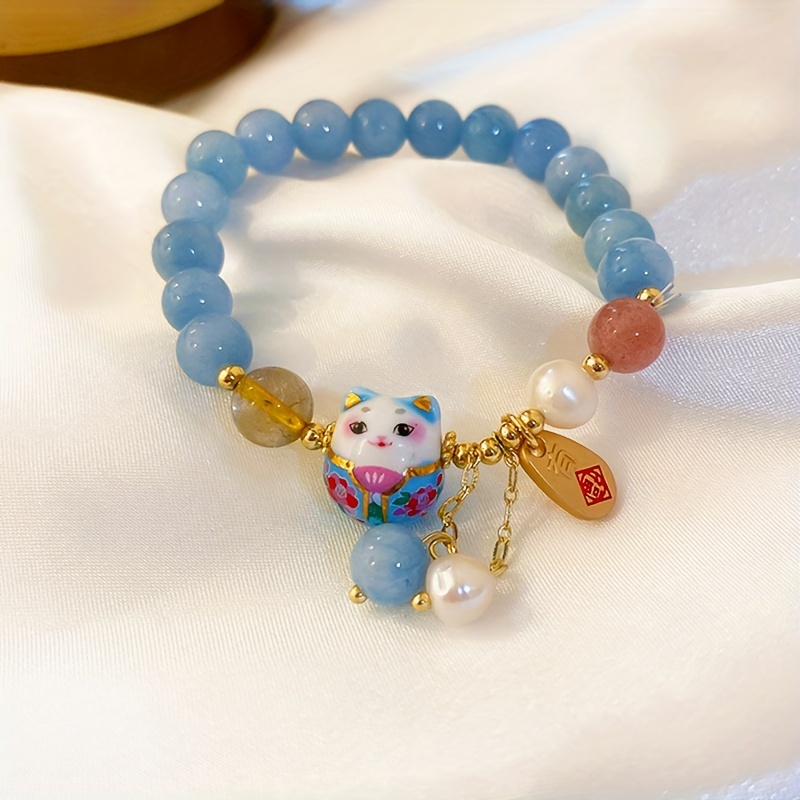 

Bracelet with traditional Chinese design featuring lucky cat-shaped beads and elegant handmade blue faux crystal beads.