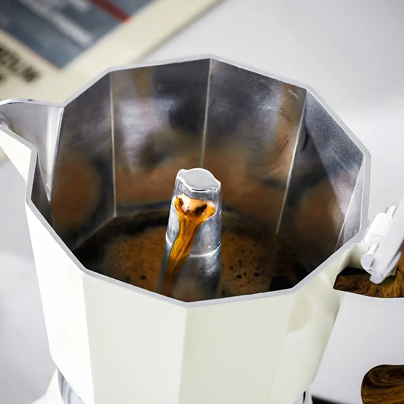 café caliente en moka pot en estufa eléctrica, cafetera vintage en