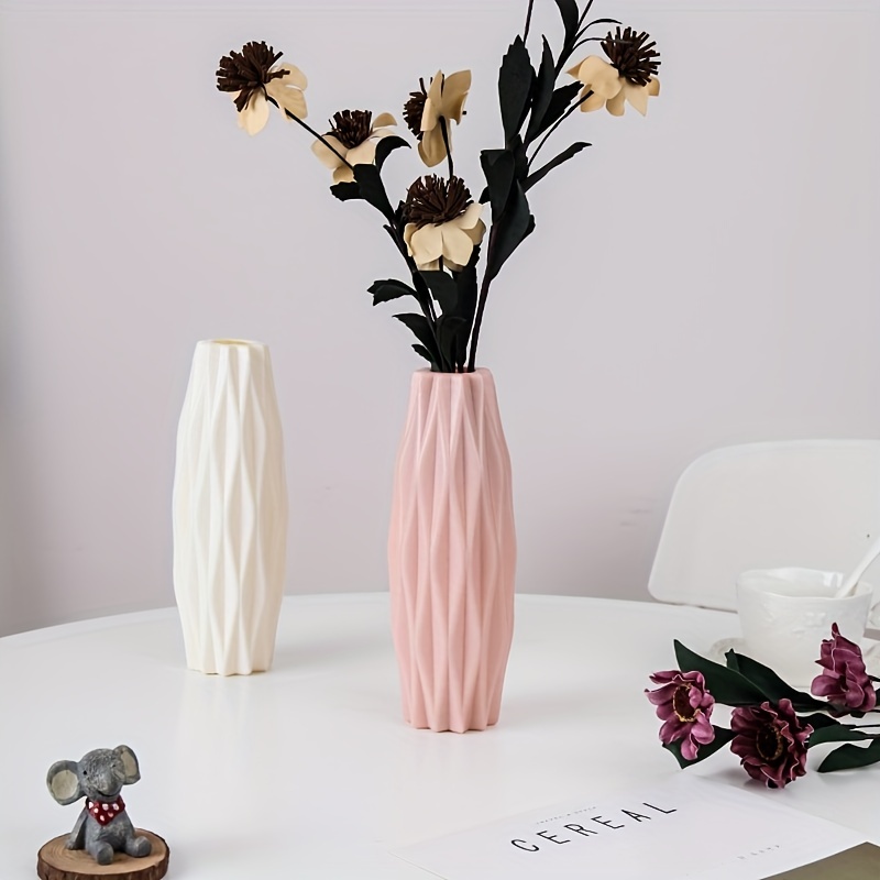 Flores artificiales en jarrones de cerámica blanca sobre la decoración de  la mesa.