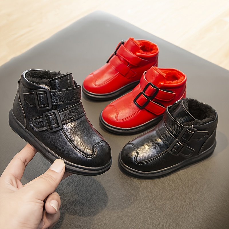 Zapatillas de deporte rojas y negras para niños zapatos para niños sobre un  fondo rojo.