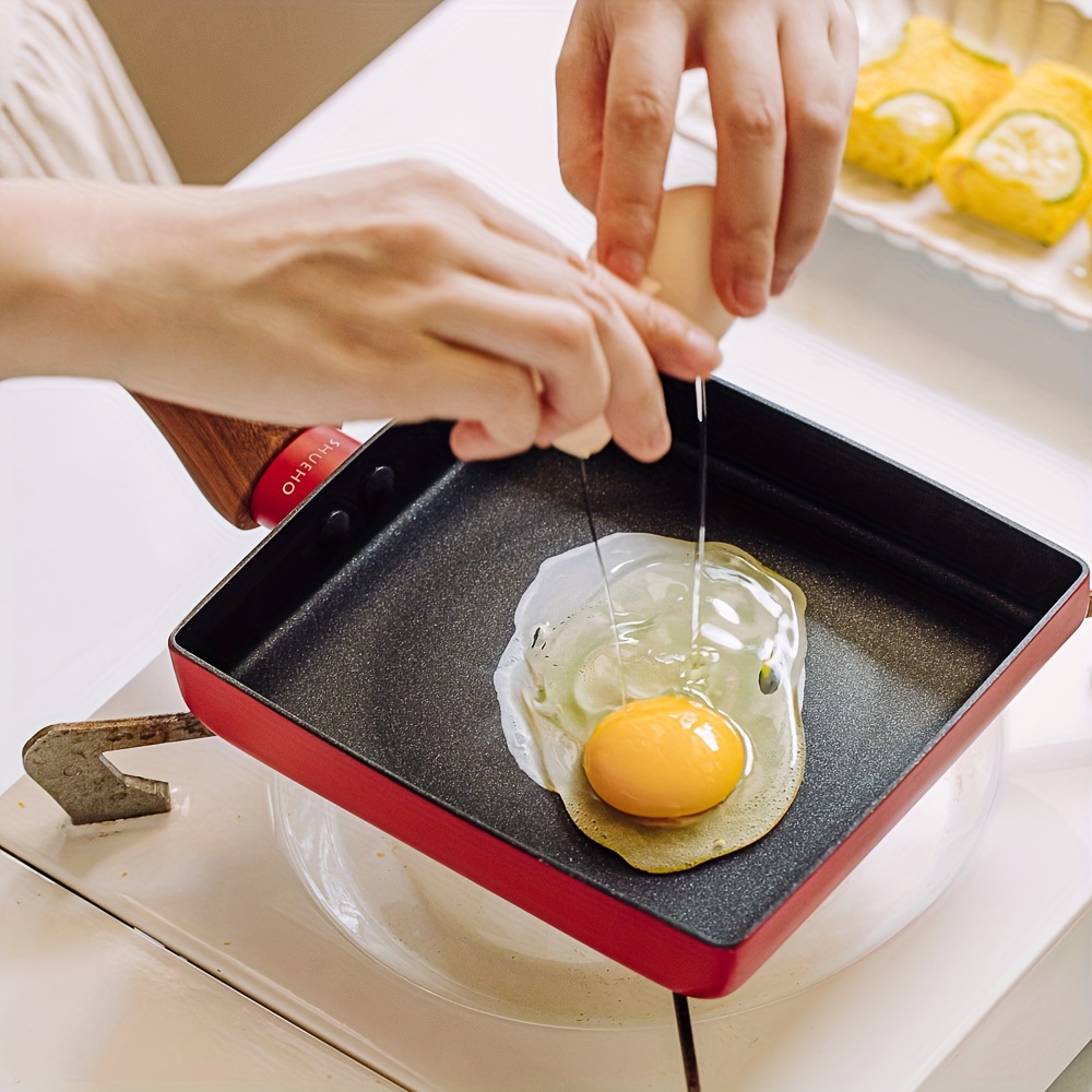 Tamaño problemático. Huevo de gran dimensión para cocinar en una sartén  pequeña y de juguete. Stock Photo