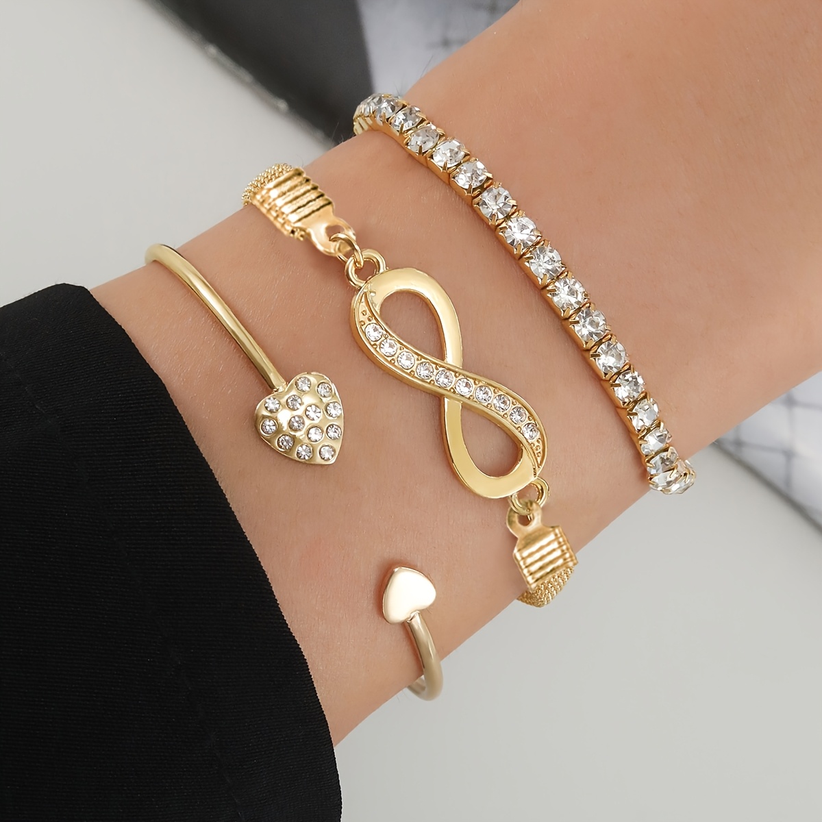 A Set of Three Women'S Bracelets And Bangles Featuring Wireless Symbols And Heart Designs Adorned with Rhinestones.