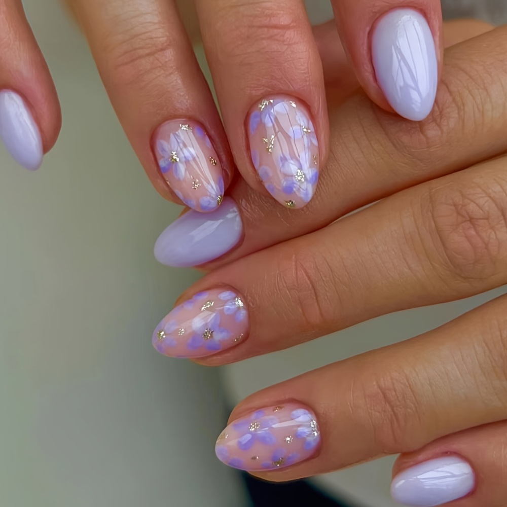 TEMU 24 uñas postizas cortas de presión, con un rosa nude transparente combinado con taro, complementadas con flores moradas pintadas a y detalles de