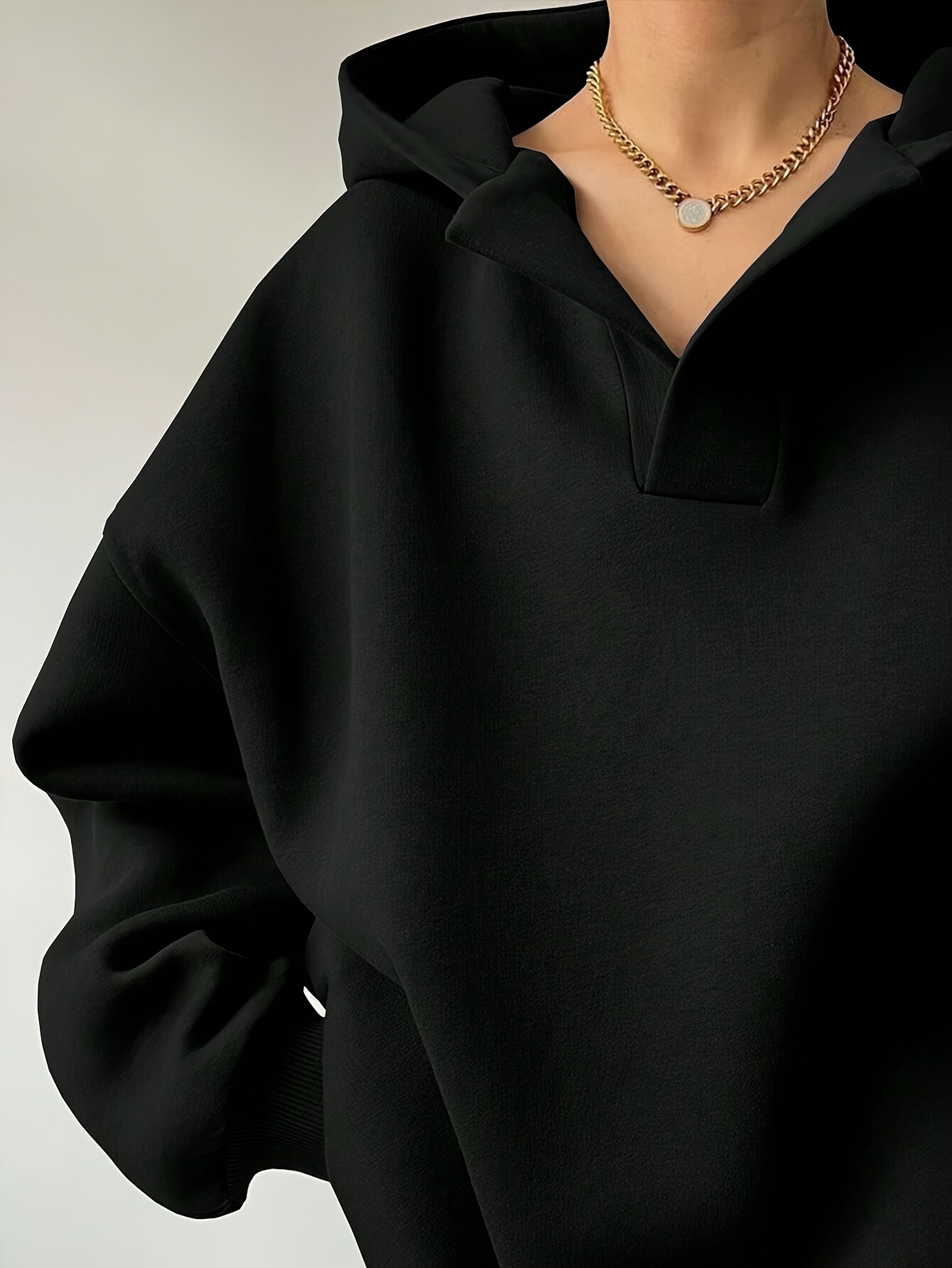 The front view of a woman wearing a black winter hoodie for women sold by 100 Spartans