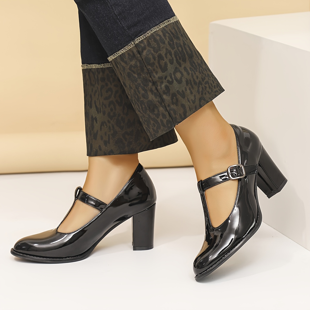 Un par de zapatos de tacón con correa en T de punta redonda y corte  para mujer en color negro para