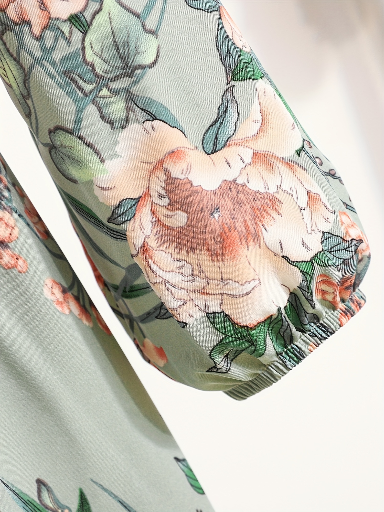 שמלה הדפסה רחבה עם שלחן גזרה ארצישראלית ווני גזרה עם פרחים ורדים ולבנים. עם צווארון עגול, מכפלת מקושטת ומותן צמודה, ירוק בהיר עם פרחים ורודים ולבנים, מושלם לאירועי אביב/סתיו, שמלה פרחונית