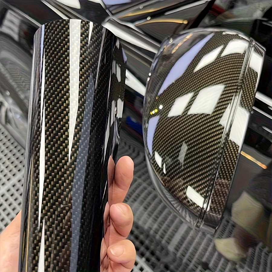 A professional installer heating a vinyl car wrap to fit a complex bumper curve.