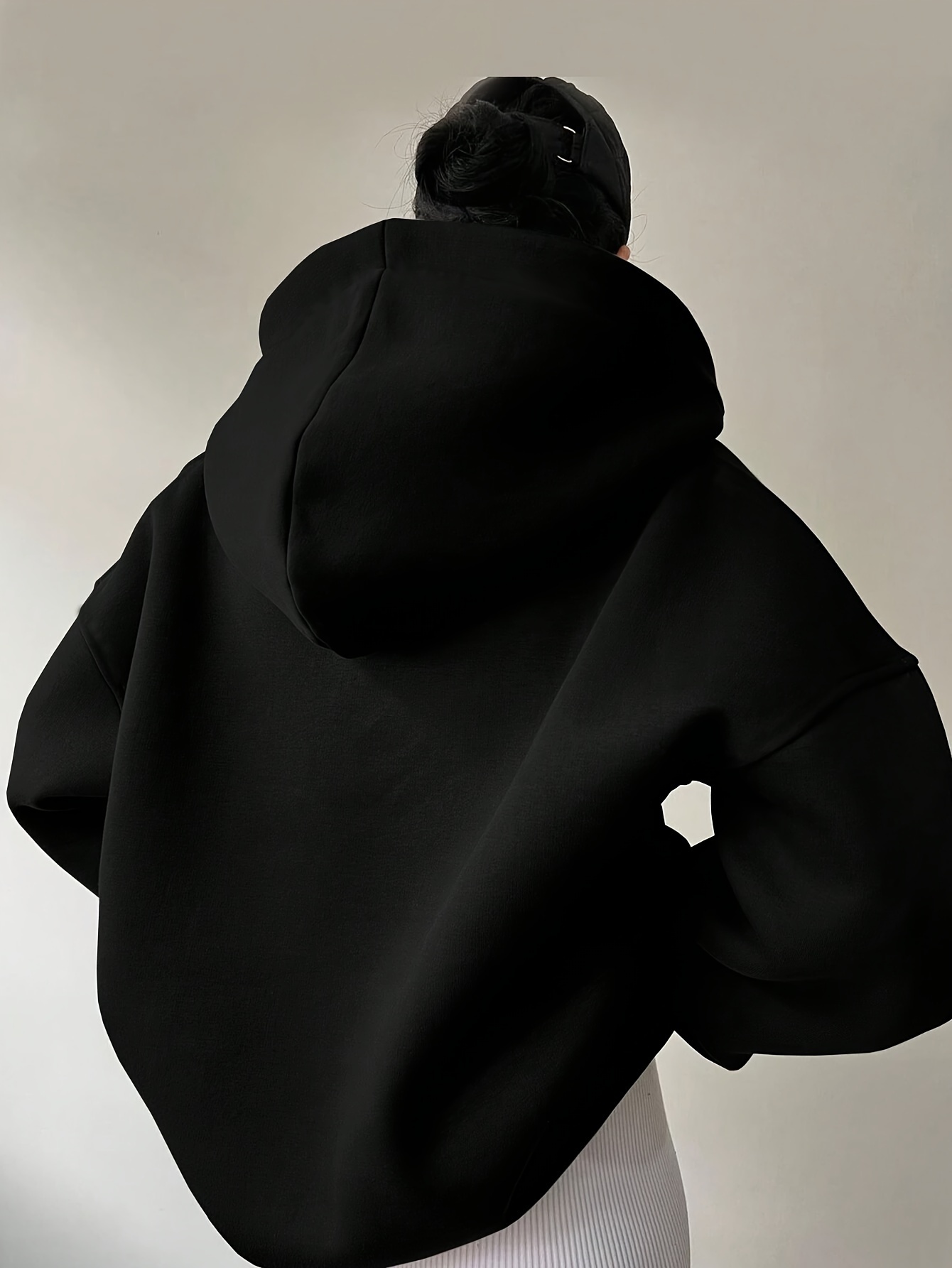 The backview of a woman wearing a black winter hoodie for women sold by 100 Spartans