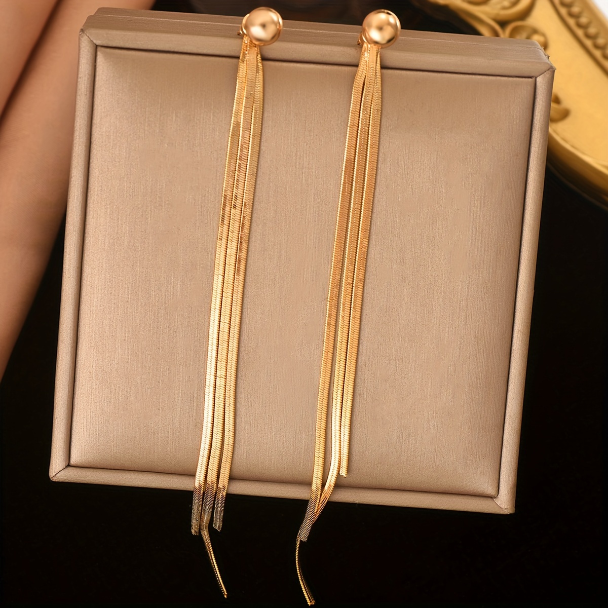 

A Pair Of Golden Plated Jewelry Tassels With . The Earrings Are Elegant, Fashionable, Simple, And , Making An For Girls And Women To Wear At Daily Gift Parties