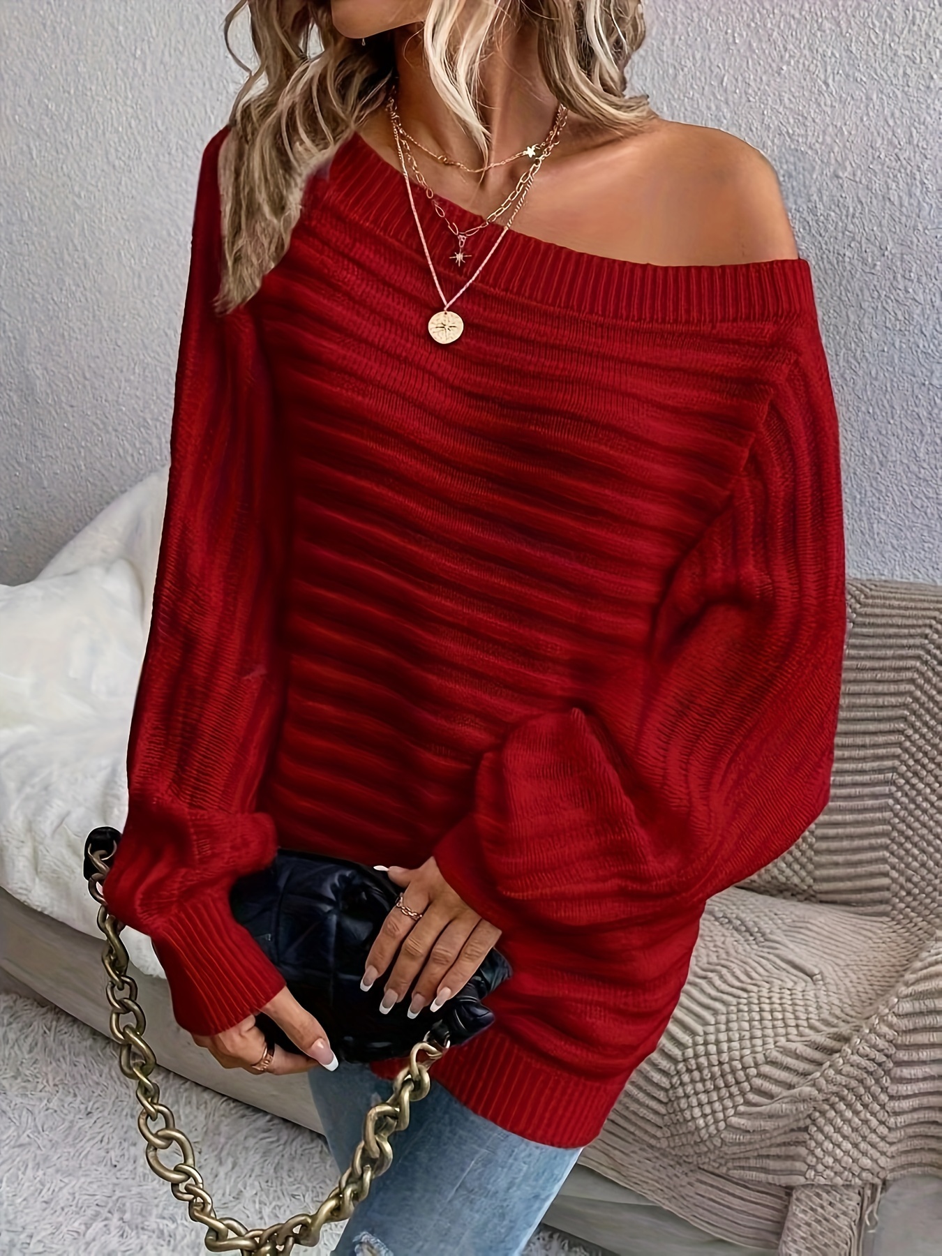 The front view of a woman wearing a red women's off the shoulder sweater sold by 100 Spartans