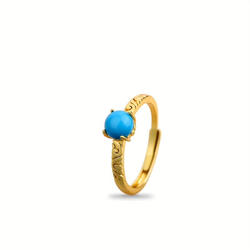 This Ring Features An Exquisite Golden Carved Band As Its Base, Set With A Round Blue Gemstone, Showcasing A Design And Elegant Aura. An Ideal Fashion For Women, For Daily Wear Or Special Occasions