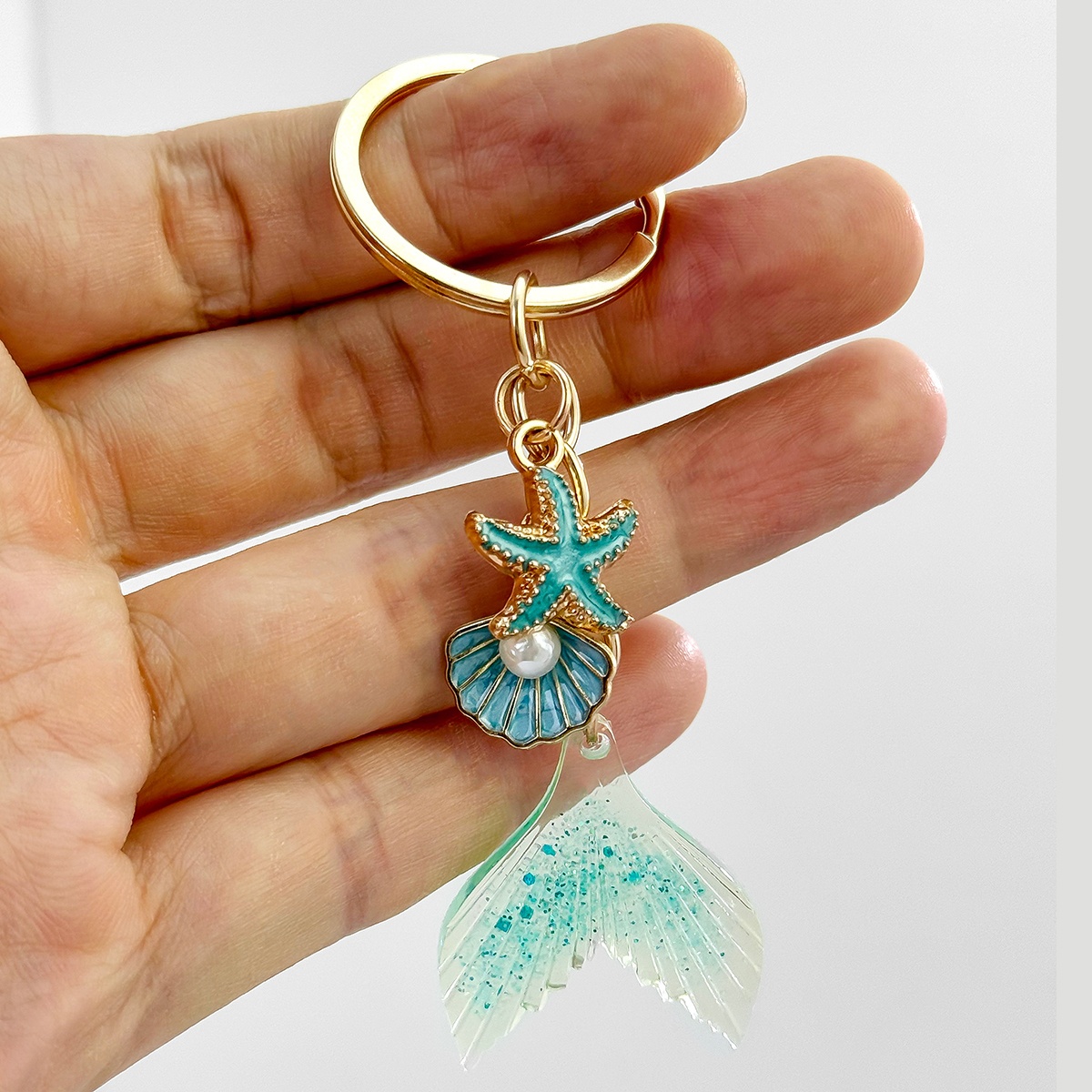 An Exquisite Mermaid Tail Keychain With Ocean-themed Glitter, Starfish, Seashells, And