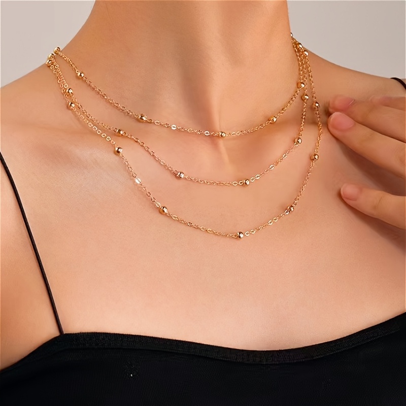 

Un élégant collier multicouche en perles dorées, un collier unique en acier inoxydable .