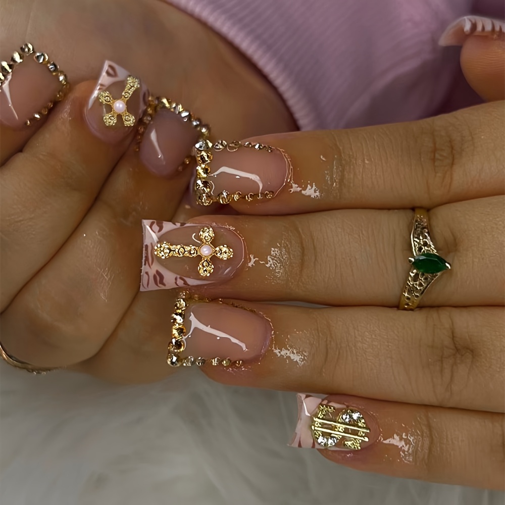 24pcs Short Duckbill Press-On Fake Nails, Featuring a Sheer Nude Pink with Pink Leopard Print Gradient, Accented with Golden Rhinestones, Three-dimensional Cross Charms, and Dollar Sign Metal Embellishments. The Glossy Top Coat Provides