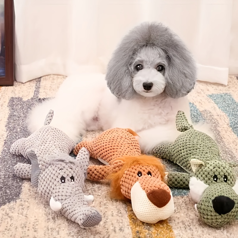 Three textured animal-shaped plush dog toys beside a dog