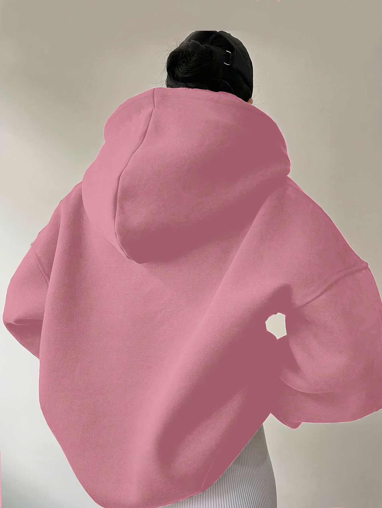 The backview of a woman wearing a pink winter hoodie for women sold by 100 Spartans