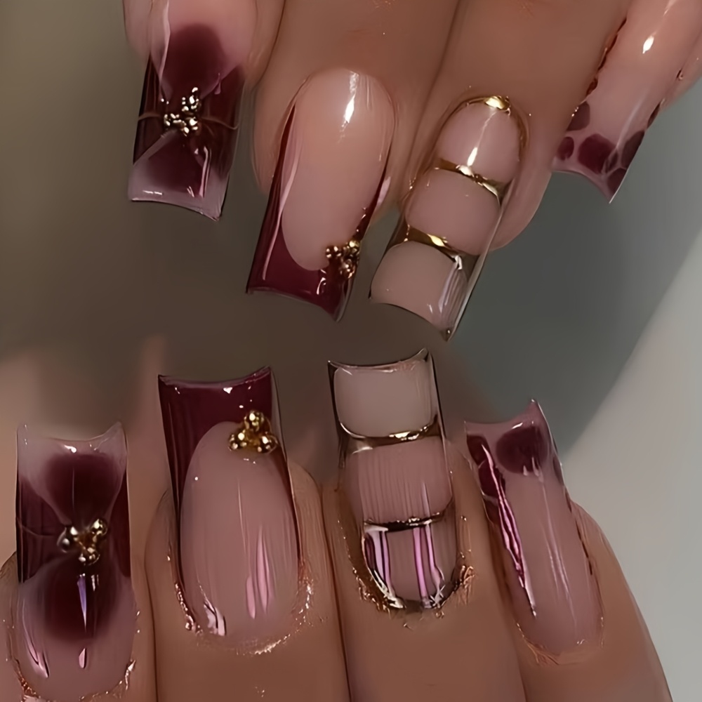 E-shop 24-teilige lange quadratische Aufklebekünstlernägel. Hauptfarben sind Nude-Rosa Burgunderrot, verziert mit metallisch-goldenen Akzenten.