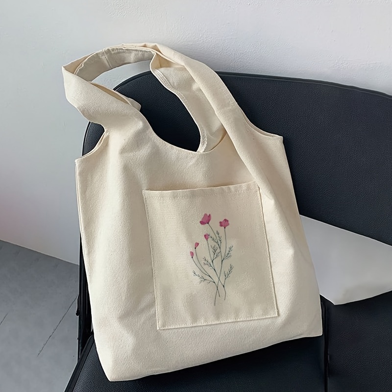 a stylish and easy beige tote bag with a plant print     serving as a   shopping bag or a canvas bag for students to carry their stationery