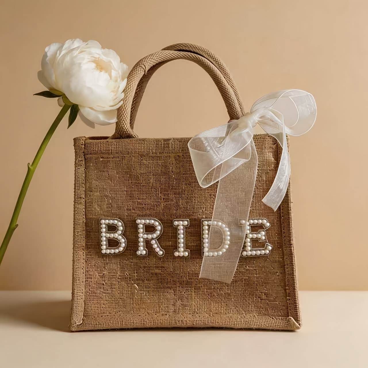 E-shop Diese einstückige Brautjungfern-Tasche aus Jute ist mit Griffen und einer Schleife aus Band ausgestattet und eignet sich ideal für