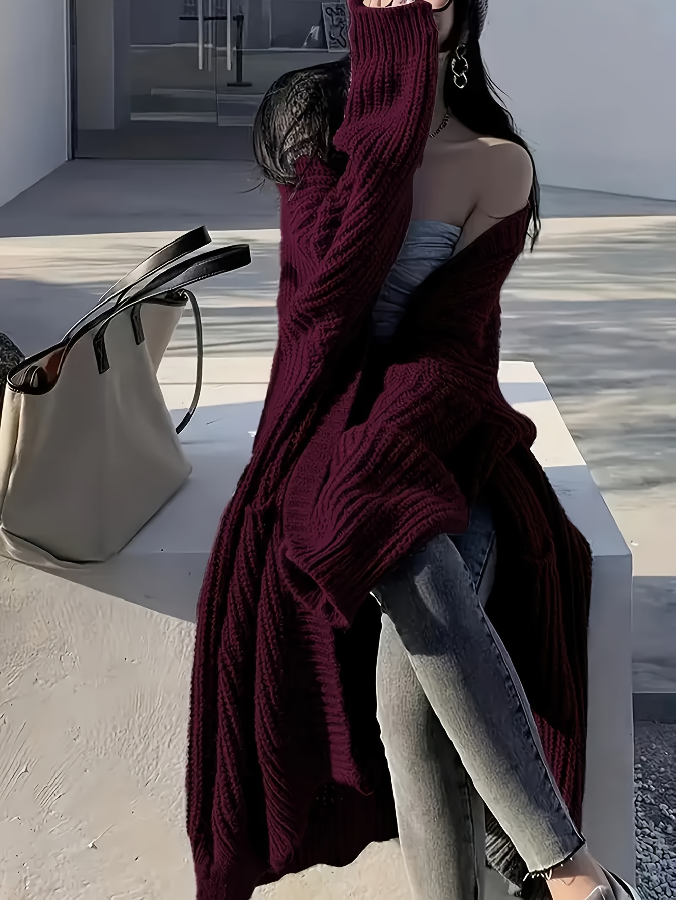 A lady wearing a dark red oversized knitted coat with pockets sold by 100 Spartans