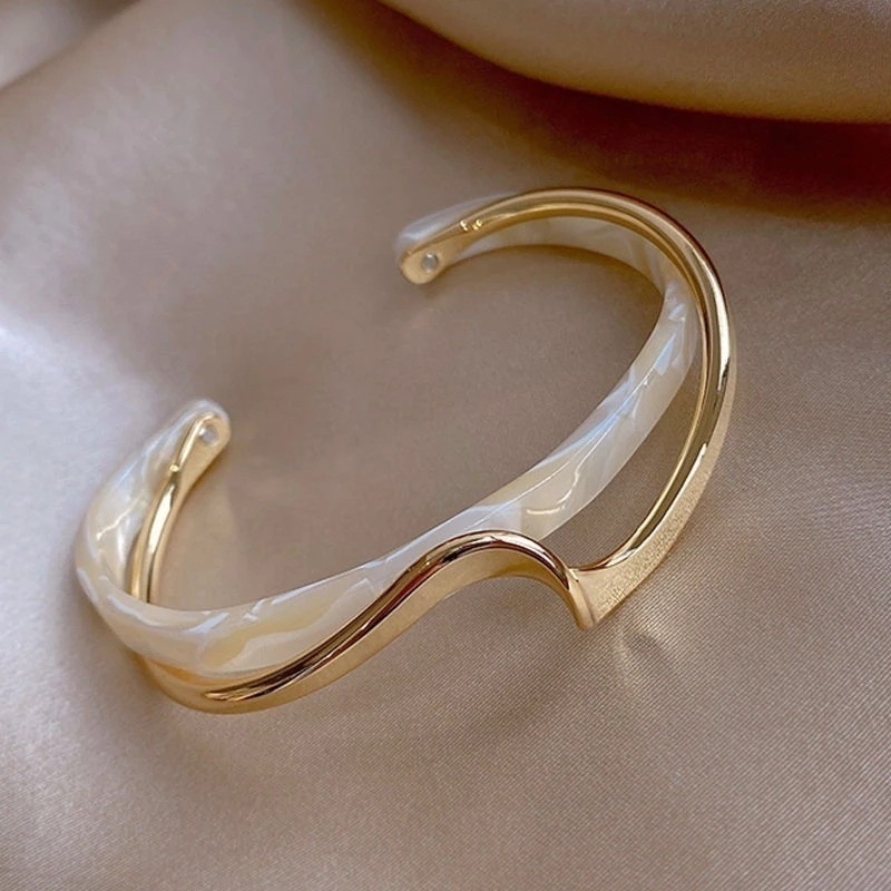 E-shop Das "Light Shell Board Armband" zeichnet sich durch eine gebogene Metallic-Textur aus. Das Armband verfügt über ein Nischen-Design und ist ein
