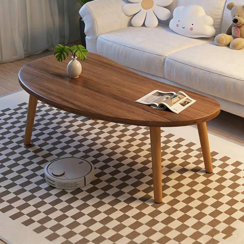 natural wood grain oval coffee table irregular solid wood top shows legs create lightweight visual cozy companion for living room reading nook holds vase and magazines displaying lifestyle modern minimalist piece