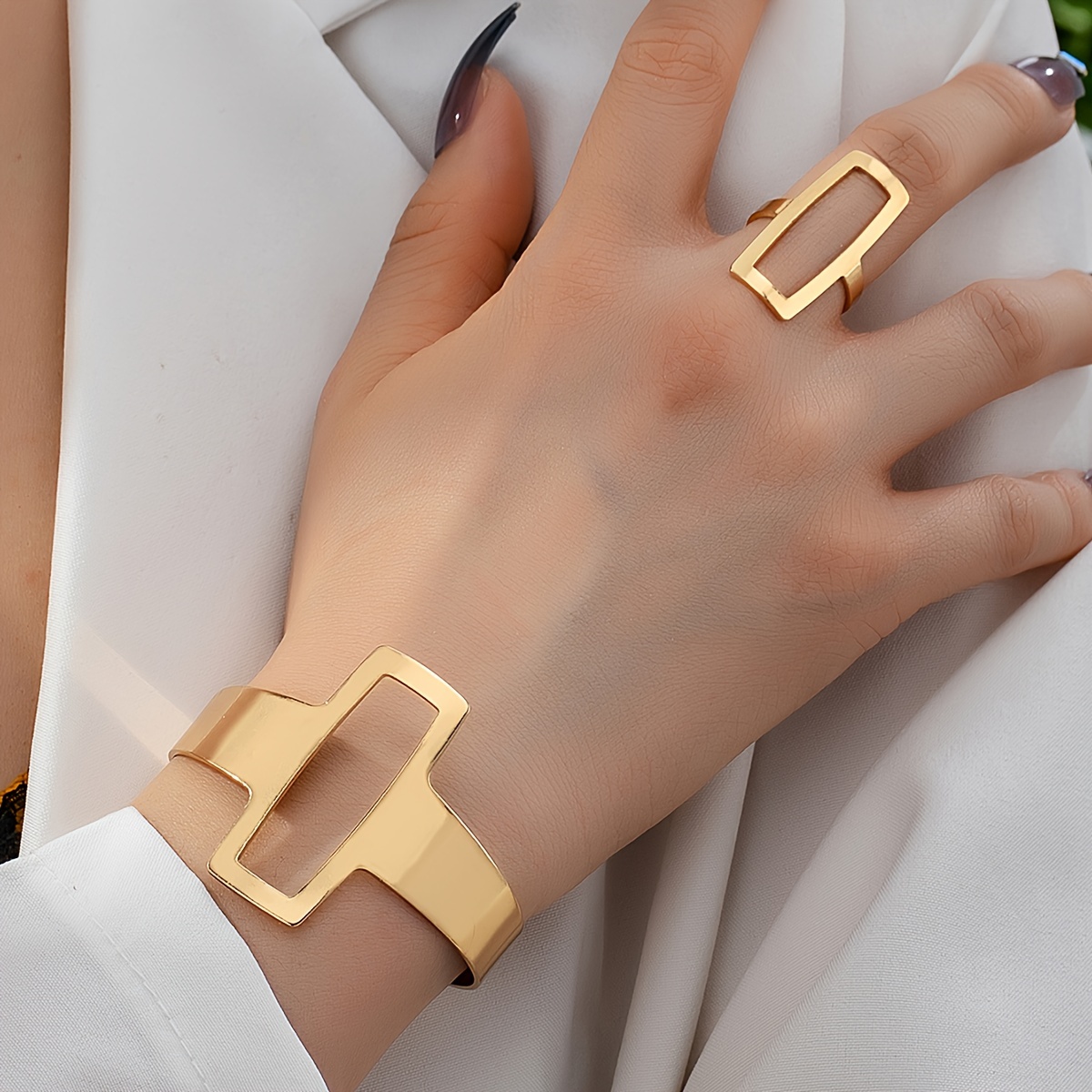 

et portant un bracelet géométrique creux et un anneau géométrique creux.