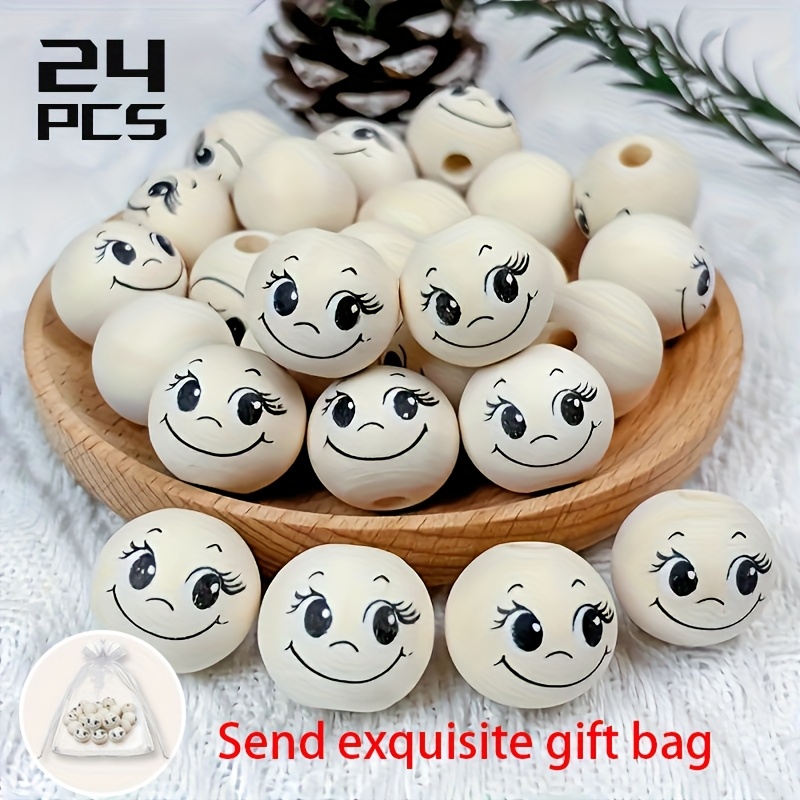 E-shop Set mit 24 übergroßen dekorativen Holzperlen mit fröhlichen, großäugigen Designs und langen Wimpern, verpackt in einer attraktiven Geschenktüte.