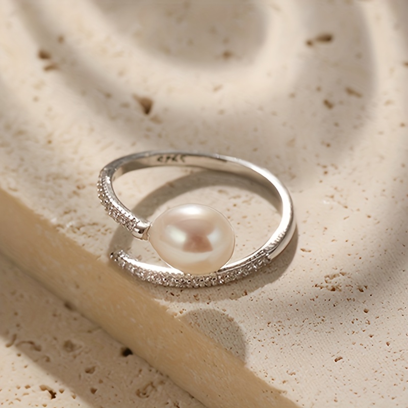 E-shop Ein Ring mit unechter Perle und ovalem, geometrischem Design. Eingefasst mit synthetischem Zirkonia, verstellbare Öffnung. Elegant und , für