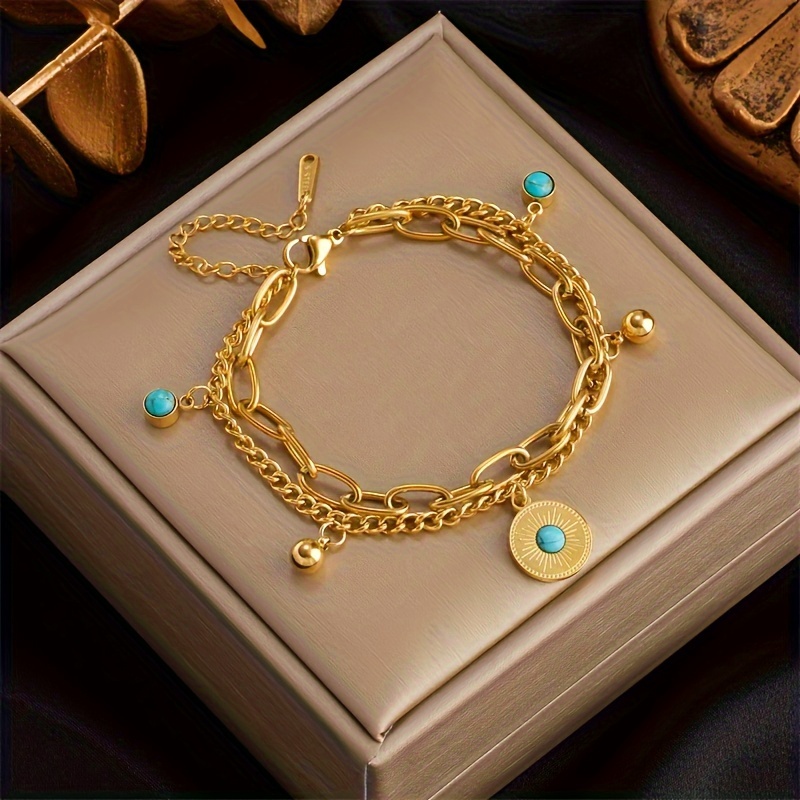 

Bijou tendance en cadeau avec un bracelet à double chaîne avec une boule turquoise et un pendentif en de pièce de monnaie en acier inoxydable dans un style hip hop rock.