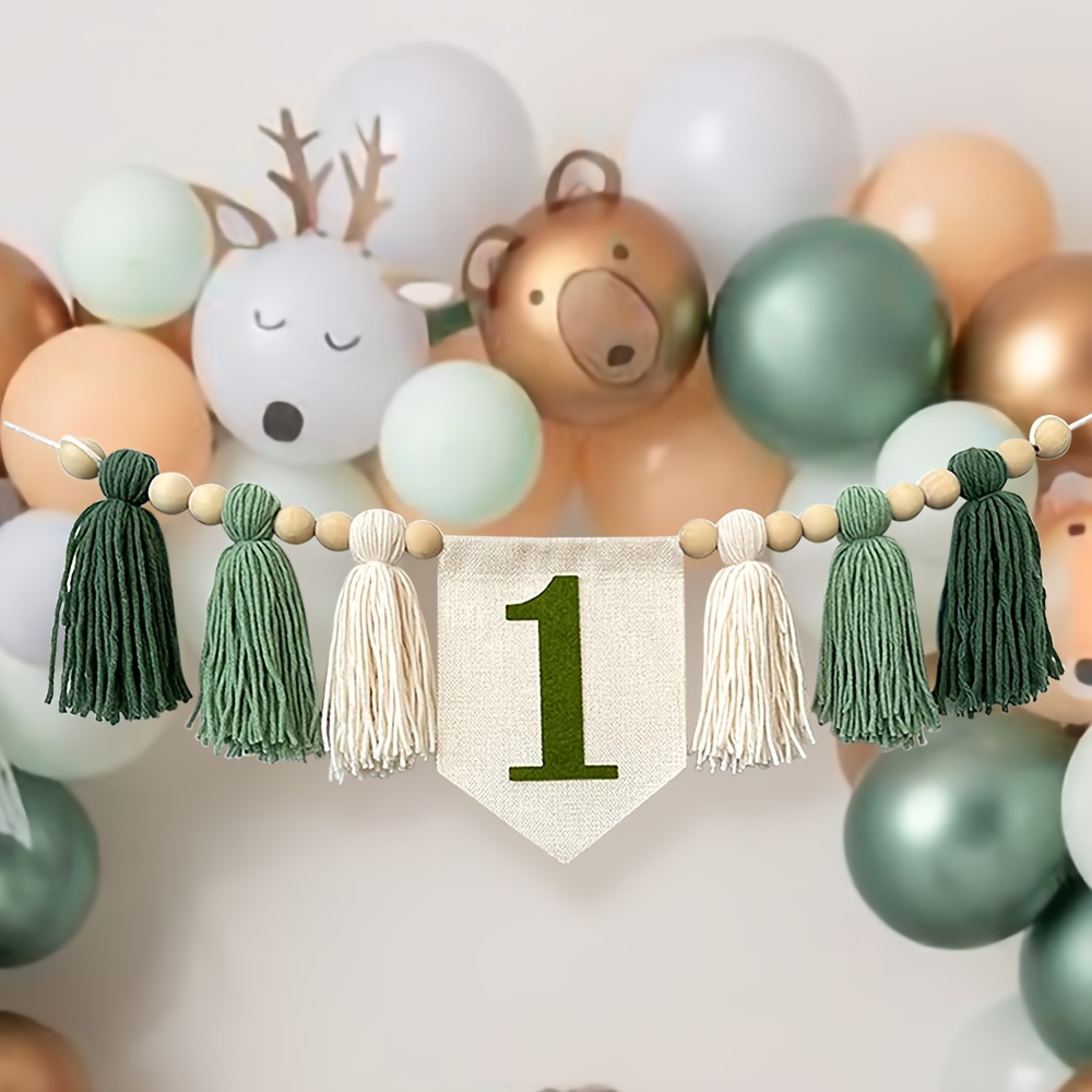 Image of A Handmade Green High Chair Banner With Dark Green Tassels And A Pull Flag Garland, Suitable For Jungle Wildlife Themed Birthday Party Decorations.