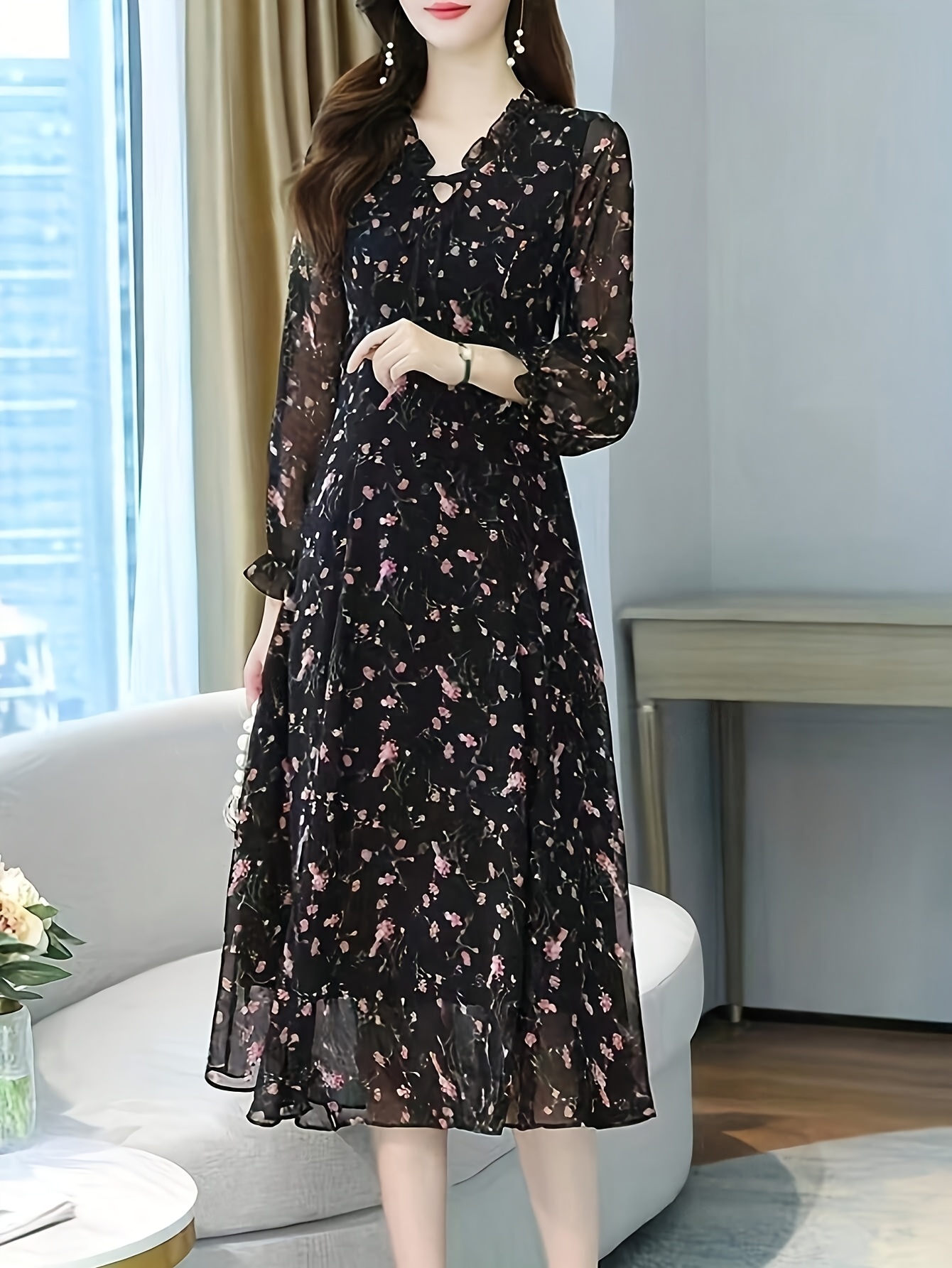 A model wearing a black maxi dress with a delicate floral print posing against a bright background