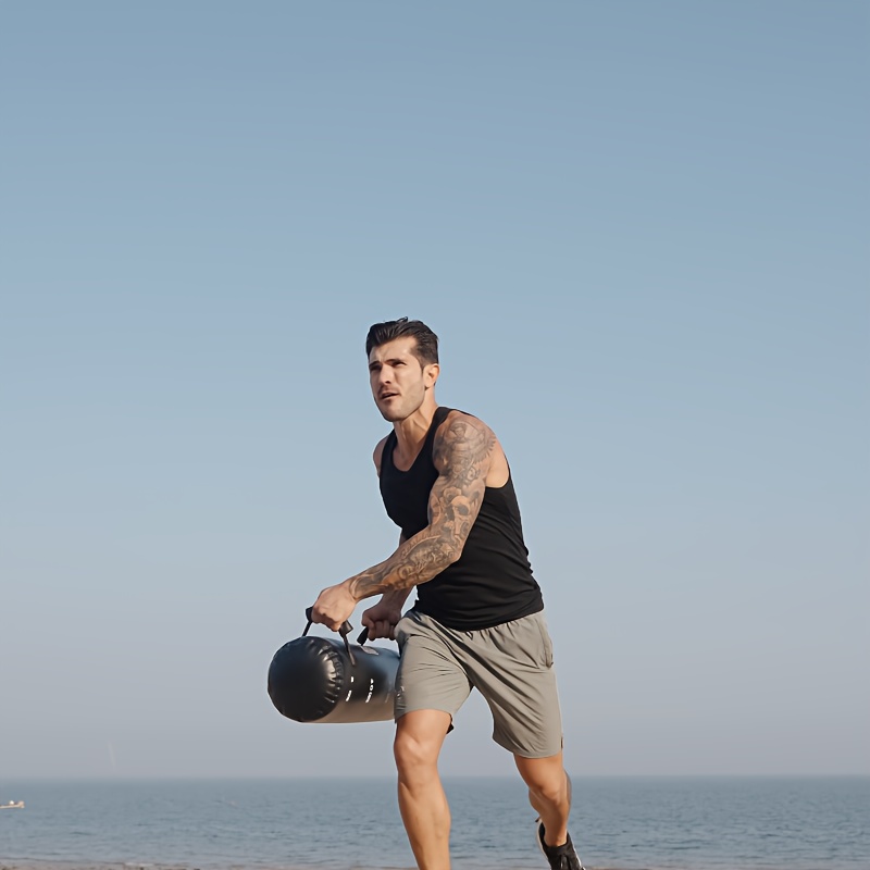 Man holding a water weight bag on a beach with a clear sky