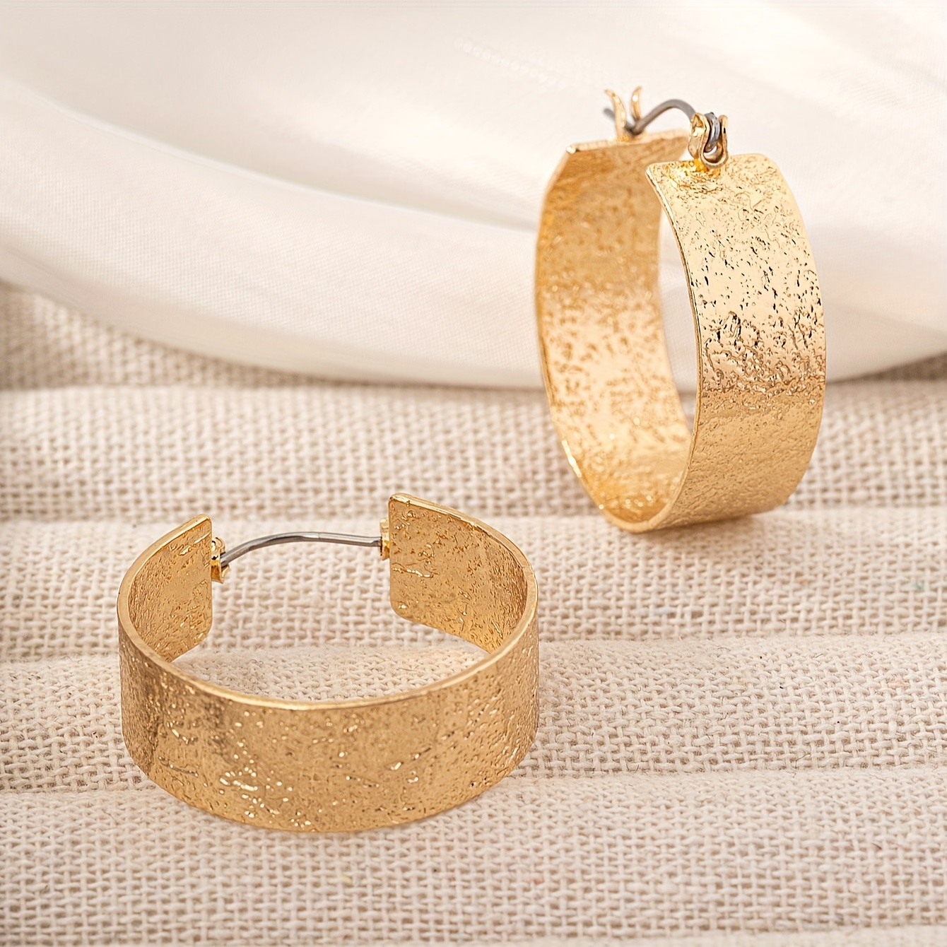 A Pair Of Stylish And Minimalist Wide-hoop Earrings With A Metallic Textured Finish, Suitable For Casual, Party, And Banquet Wear