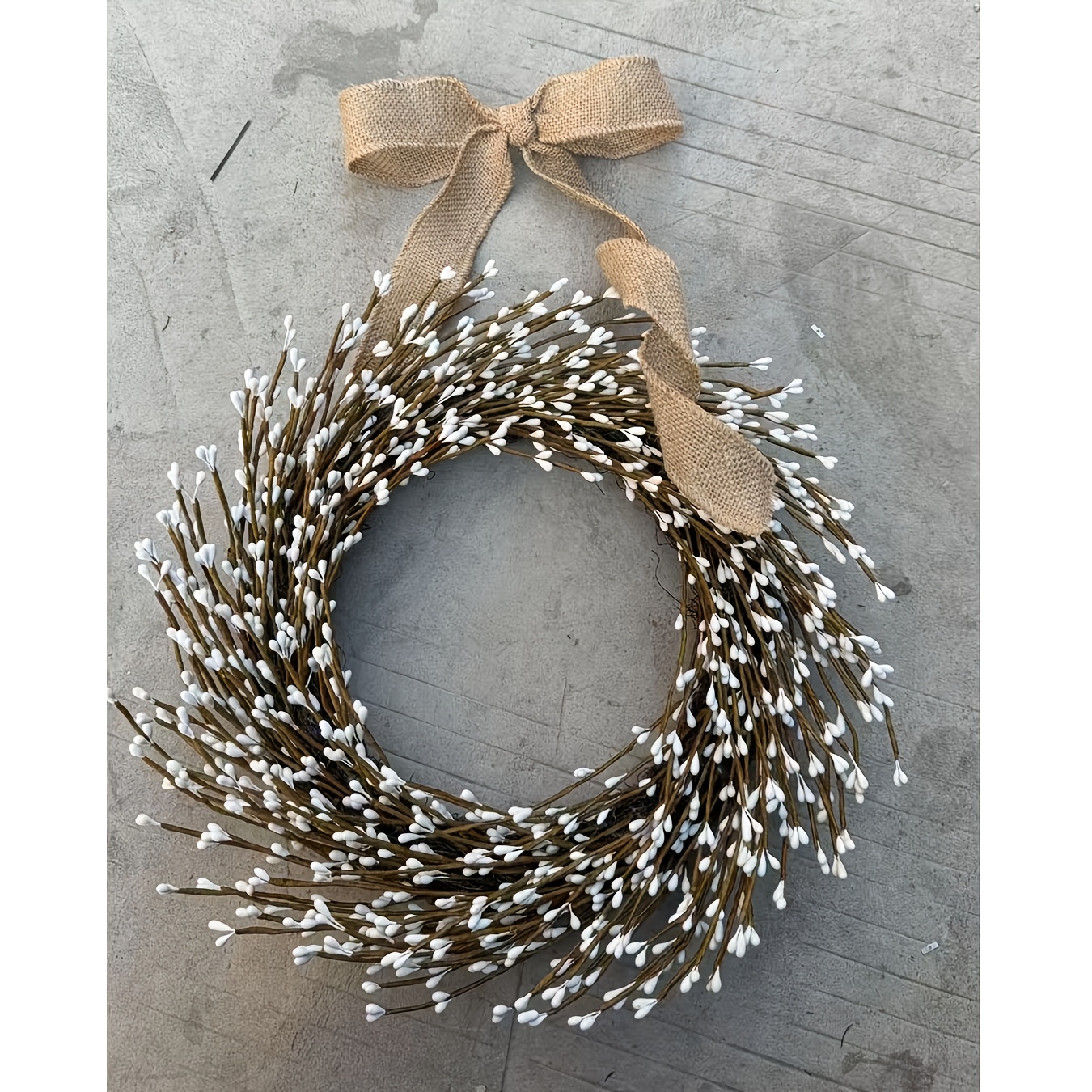 A Stylish Wreath Made Primarily Of Dark Branches With Tiny White Blossoms And Finished With Brown Bow , Perfect For Displaying On Doors, Walls, And More