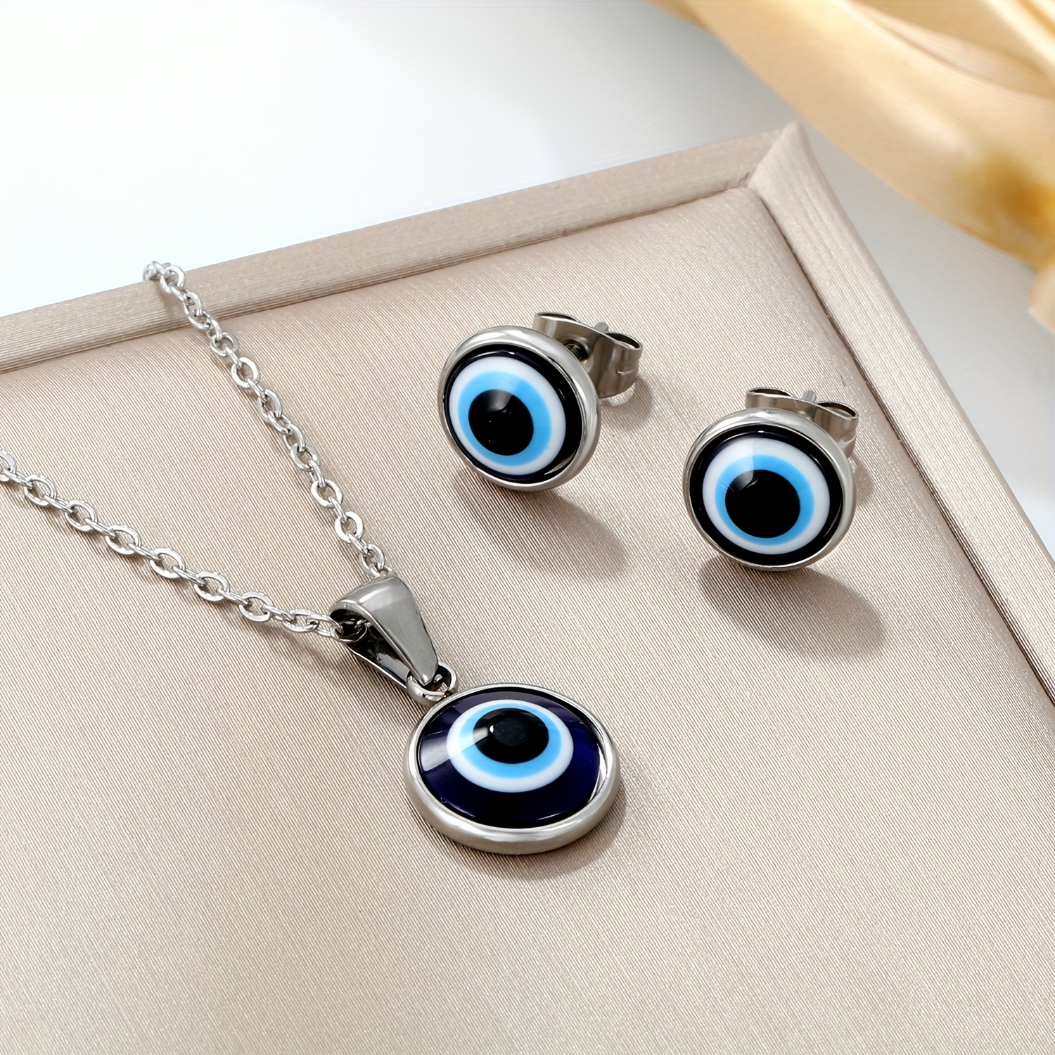 Image of A Set Of Stainless And Evil Eye Pendant Necklace And Stud Earrings. The Eye Necklace And Earrings Set For Women Features A Designer Aesthetic, Luxury, High-end, , And Minimalist Instagram-.